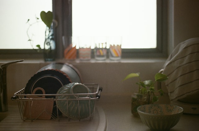 Dishes beside kitchen sink underneath a window